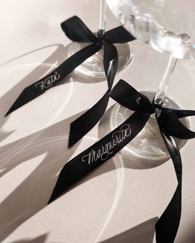 Marque-place tendance dorure argentée sur ruban noir noué autour du verre
